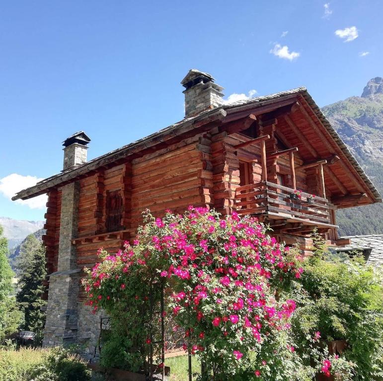 a log cabin with flowers in front of it at Au Rascard in Brusson