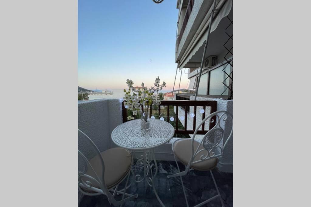 een tafel en stoelen op het balkon van een gebouw bij RUSTIC DIAMOND new apartment near the beach in Porto Rafti
