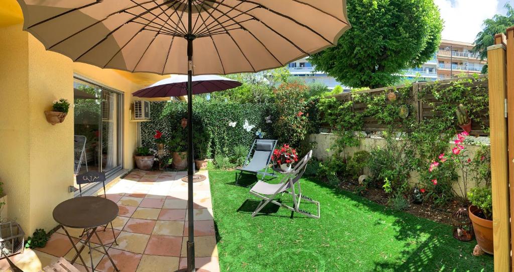 eine Terrasse mit einem Sonnenschirm, 2 Stühlen und einem Tisch in der Unterkunft Marion plage in Cagnes-sur-Mer