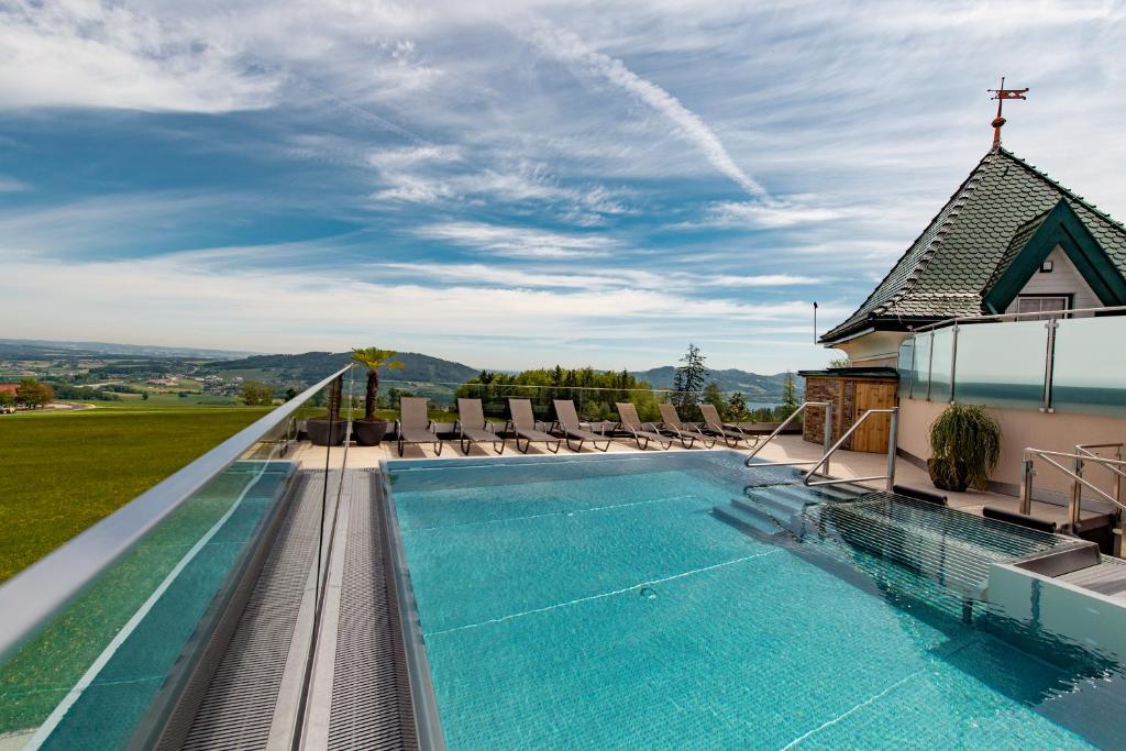 a swimming pool with chairs and a church at Hotel Irmgard in Strass im Attergau