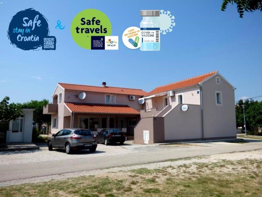 ein Gebäude mit einem auf einem Parkplatz geparkten Auto in der Unterkunft Apartments Branko Nin in Nin