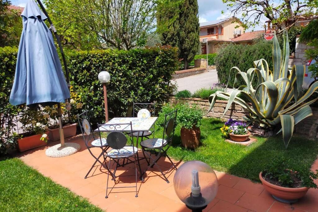 patio ze stołem, krzesłami i parasolem w obiekcie L' Agave - Appartamento nel cuore del Chianti w mieście Castelnuovo Berardenga