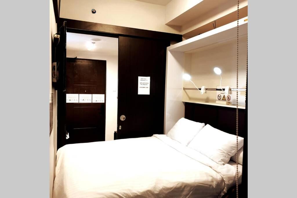 - une chambre avec un lit blanc et un miroir dans l'établissement @Mojo Smart Apartment - Begawan Apartment, à Dau