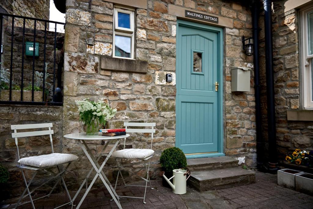 a table and chairs in front of a building with a blue door at Maltings Cottage in Barnard Castle