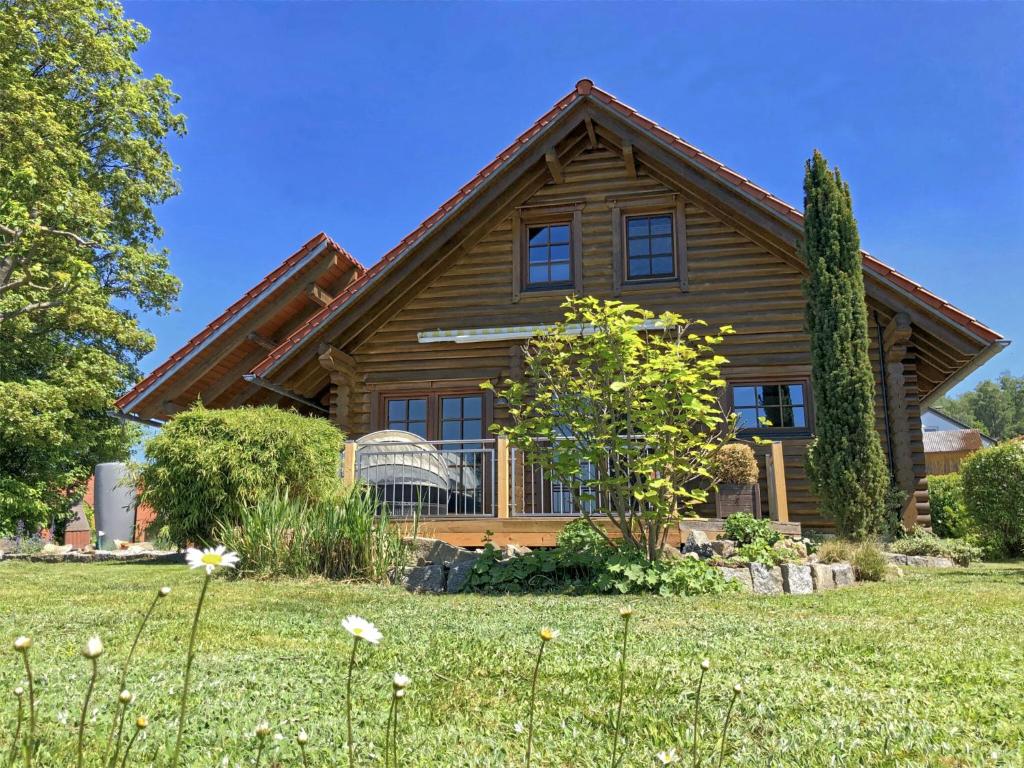 a large wooden house with a green yard at Comfortable holiday home with hot tub in Teunz