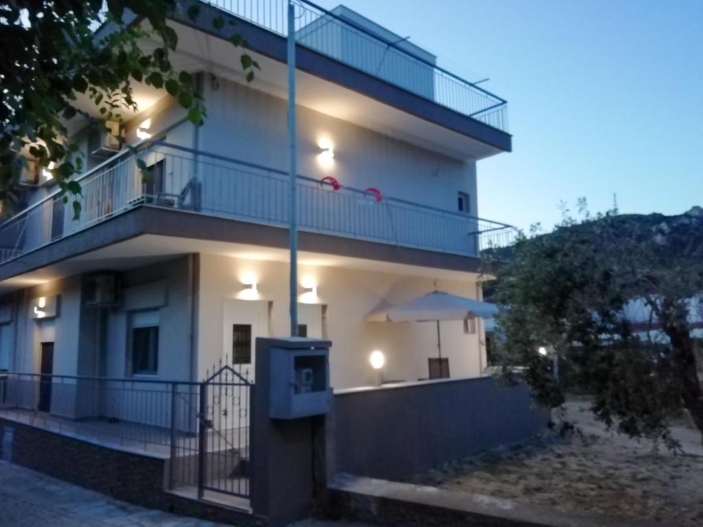 a white building with a balcony and an umbrella at ANEMOELIA II in Sykia Chalkidikis