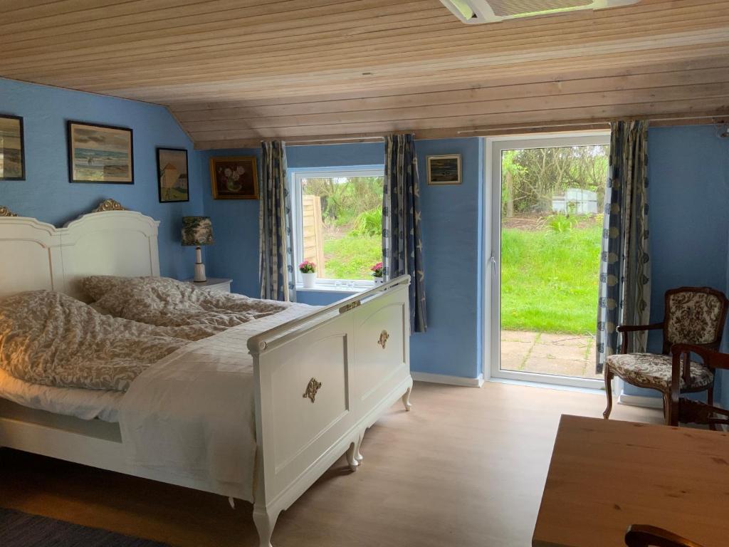 een slaapkamer met een bed met blauwe muren en ramen bij Brogaard Apartments in Løkken