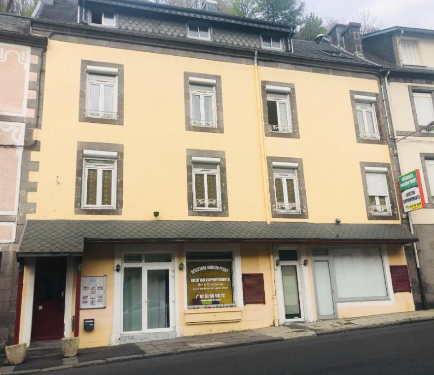 un bâtiment jaune sur le côté d'une rue dans l'établissement Résidence Bardon-Perry, à Le Mont-Dore