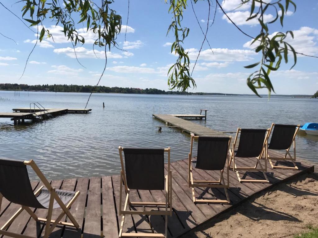 eine Gruppe von Stühlen, die auf einem Dock auf einem See sitzen in der Unterkunft Apartamenty i pokoje Seeblick in Mikołajki