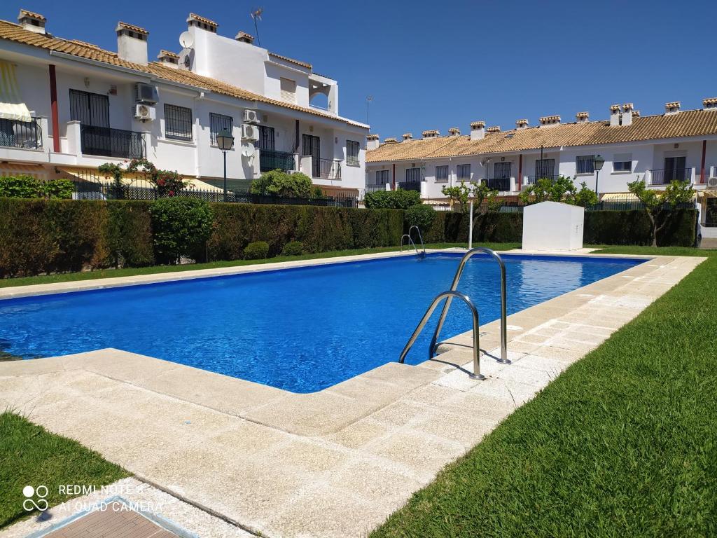 uma piscina em frente a alguns edifícios em Gran adosado de esquina muy cerca de la playa en la Antilla em Huelva