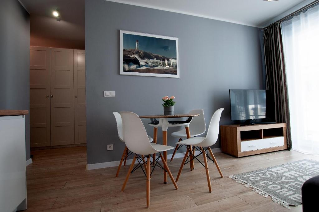 un soggiorno con tavolo, sedie e televisione di Apartament IKAR - 2 pokojowy przy morzu z balkonem a Pobierowo