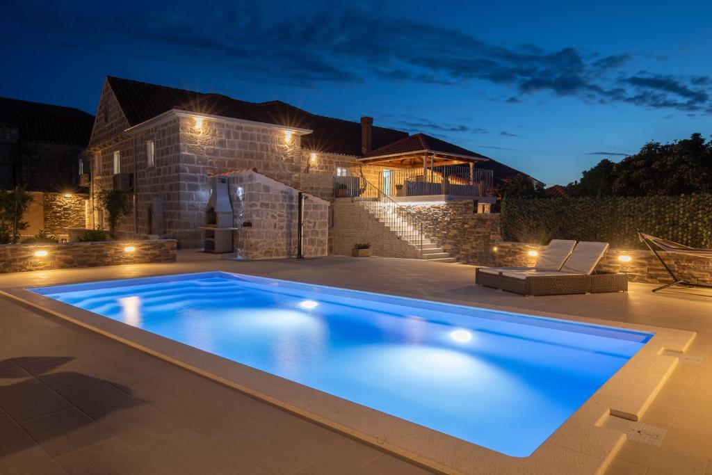 a swimming pool in front of a house at night at Villa Dalma in Čilipi