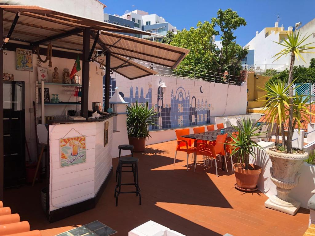um pátio no último piso com um bar, mesas e cadeiras em Orange Terrace Hostel em Albufeira