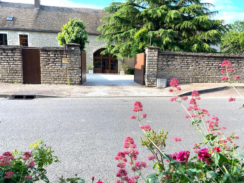 a house with a stone wall and flowers in front of it at Maison Belles Pierres in Montagny-lès-Beaune