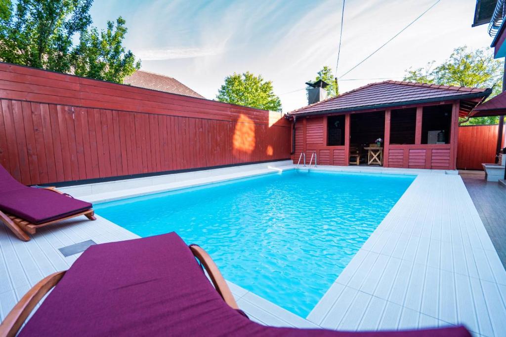 a swimming pool with two chairs and a red fence at Holiday Home Ajna in Bihać