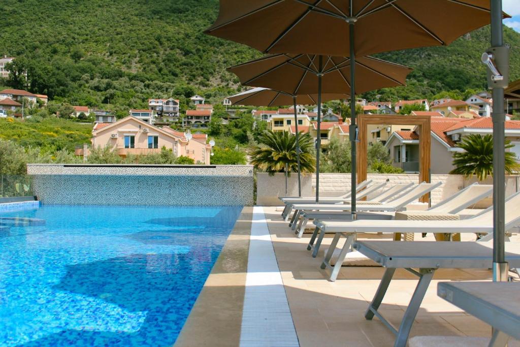 basen z leżakami i parasolami na terenie ośrodka w obiekcie Apart Hotel Sun Village w mieście Herceg Novi