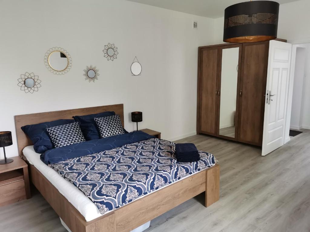 sypialnia z łóżkiem z niebieskimi poduszkami i lustrem w obiekcie Kamienica nad Maltą- Mieszkania nad Jeziorem Maltańskim w Poznaniu