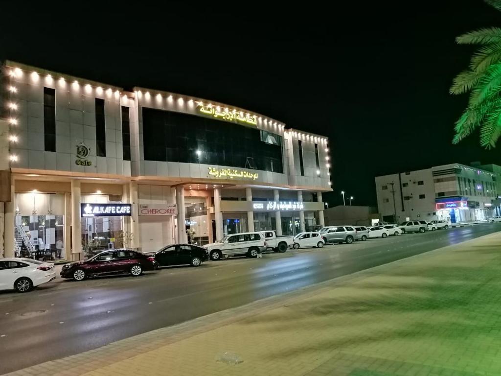 ein Parkplatz mit Autos vor einem Gebäude in der Unterkunft Fakhamat Al Orjoana & Suites in Sakaka