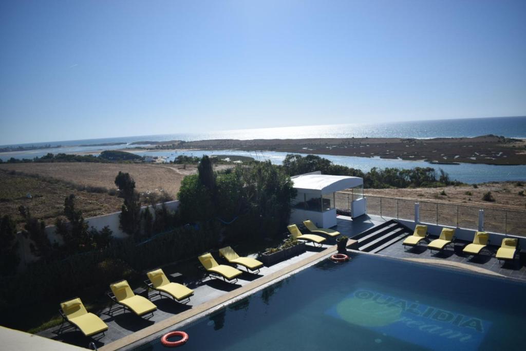 a view of a pool with lounge chairs and the ocean at Auberge Oualidia Dream in Oualidia