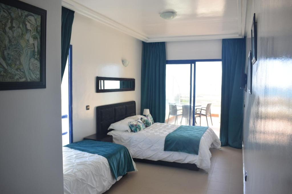 a hotel room with two beds and a balcony at Auberge Oualidia Dream in Oualidia