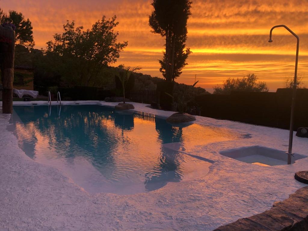 a swimming pool with a sunset in the background at Cabañas De Madera Y Bungalows - Gilmañas 3 in La Iruela