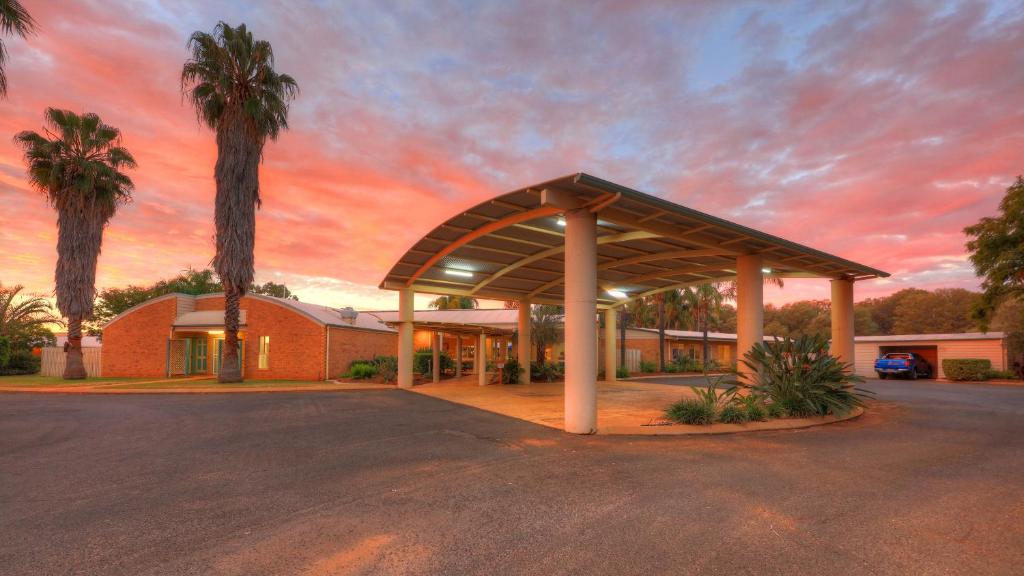 un edificio con palmeras frente a la puesta de sol en Mulga Country Motor Inn en Charleville