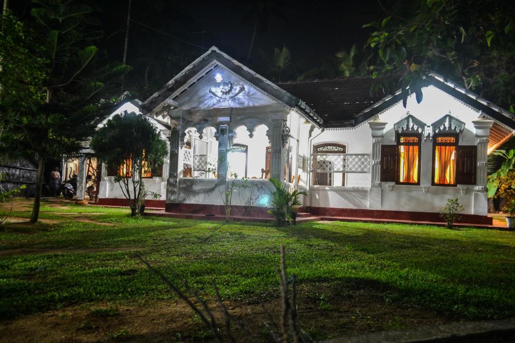 una casa blanca con césped delante de ella por la noche en Grand Villa Hikkaduwa, en Hikkaduwa