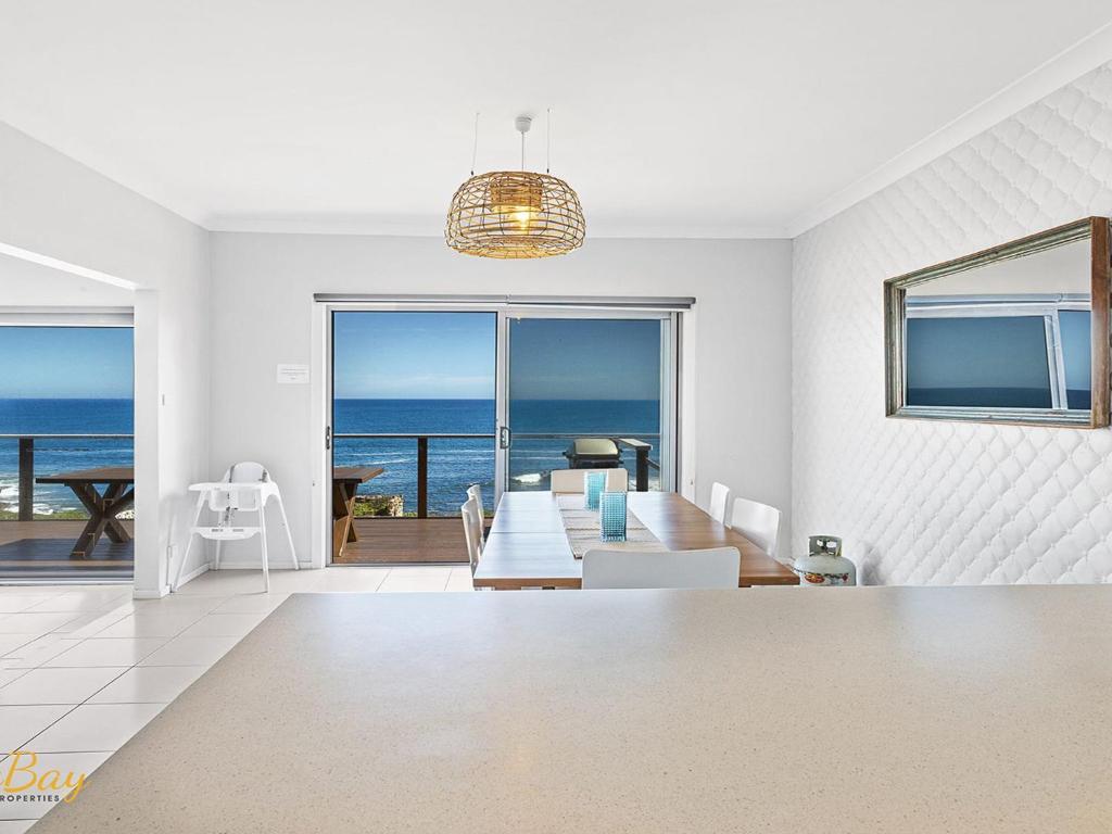 a living room with a table and a view of the ocean at Elanora Ocean St No 8 in Anna Bay