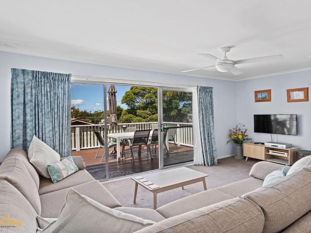 a living room with a couch and a television and a deck at Lentara Street No 31 in Fingal Bay