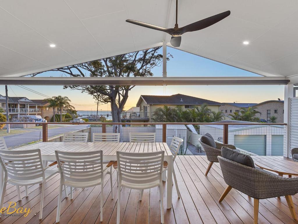 a deck with a table and chairs and a ceiling fan at Twilight on Sunset Beach Soldiers Point in Soldiers Point