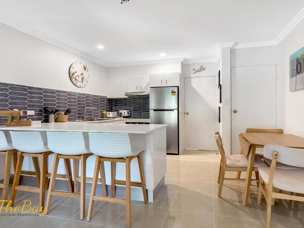 a kitchen with a table and chairs and a refrigerator at Karinya at Little Beach Downstairs in Nelson Bay