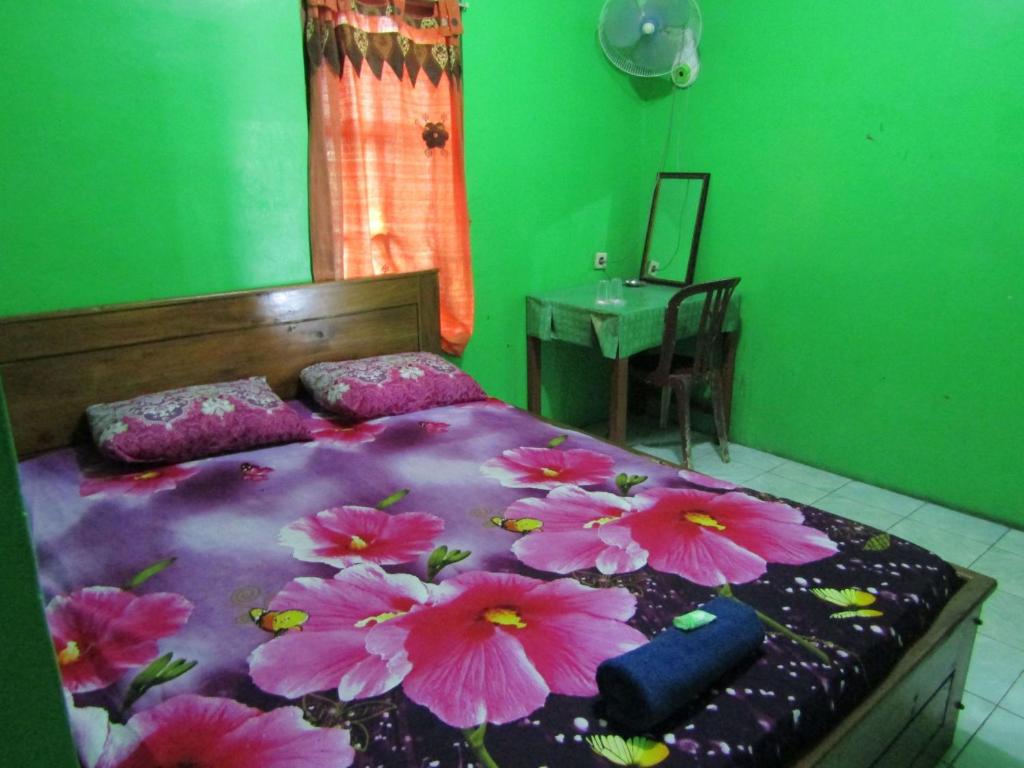 Losmen Kinasih Puncak & Gazebo Pandang في بانتول: غرفة نوم مع سرير مع زهور وردية عليه