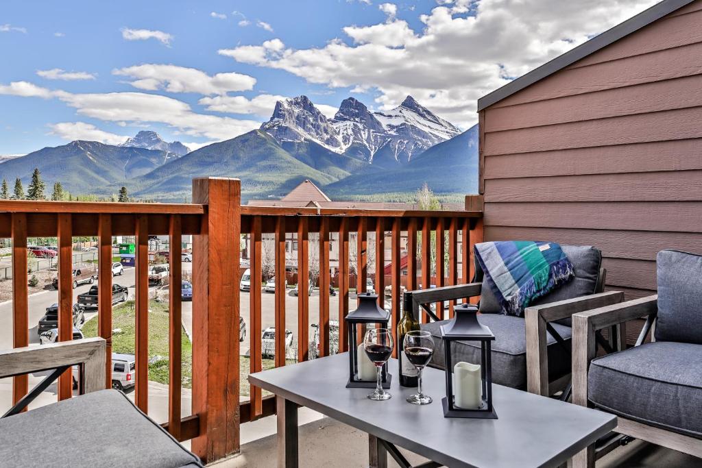 einen Balkon mit einem Tisch, Stühlen und Bergen in der Unterkunft Stoneridge Mountain Resort Condo hosted by Fenwick Vacation Rentals in Canmore
