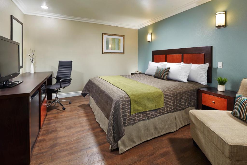 Cette chambre comprend un lit et un bureau. dans l'établissement American Inn Downey, à Downey