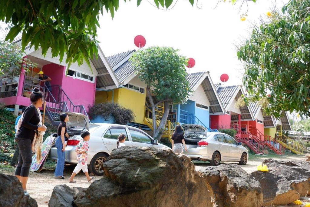 un grupo de personas caminando por una calle con casas en Baan Rai Pray Rung Kaeng Krachan, en Ban Tha Ling Lom