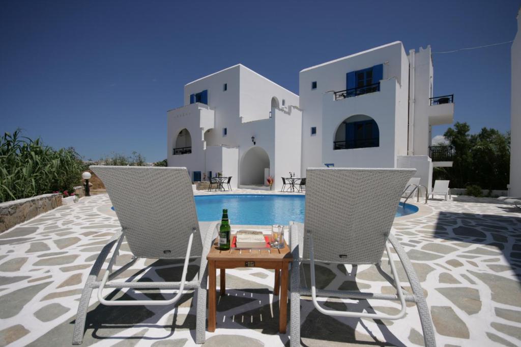 2 sillas y una mesa junto a la piscina en Sunny Beach Studios, en Naxos Chora