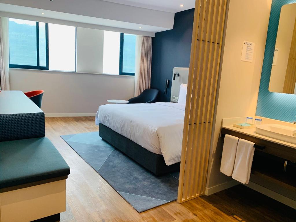 重慶市にあるHoliday Inn Express Chongqing Airport Zone, an IHG Hotelのベッドとバスルーム付きのホテルルームです。