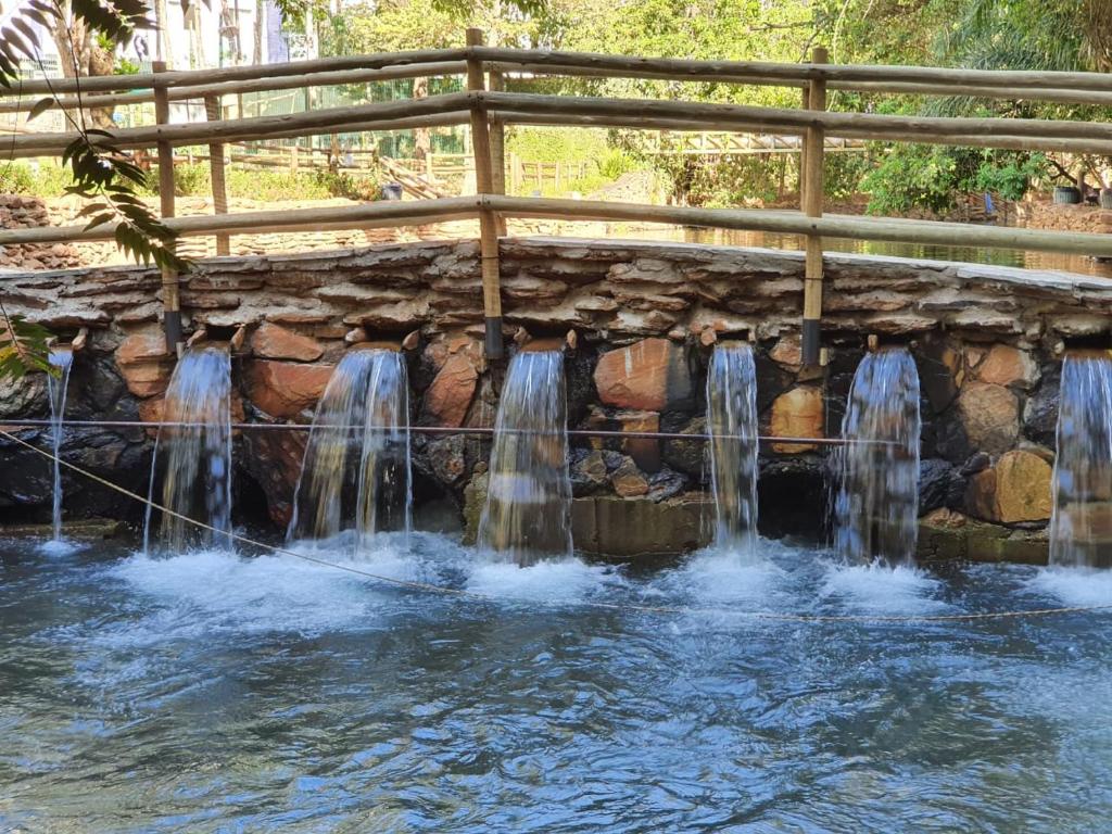 een waterval in een zwembad onder een brug bij Thermas Paradise 2Quartos in Rio Quente