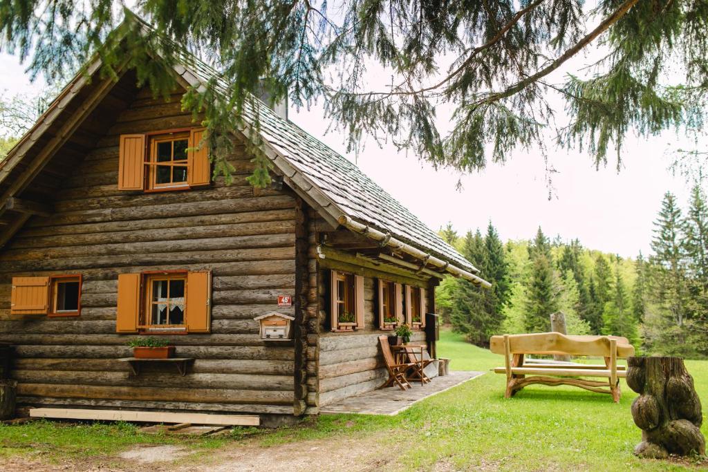 una cabaña de madera con un banco delante en Wood house Irena-Počitniška hiša, en Bohinj