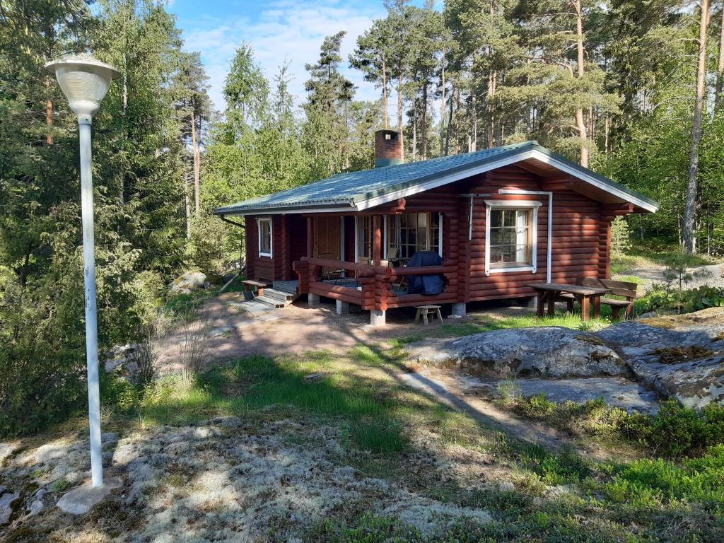 una cabaña de madera en el bosque con un poste de luz en Lomamökki Mäntylä en Töfsala