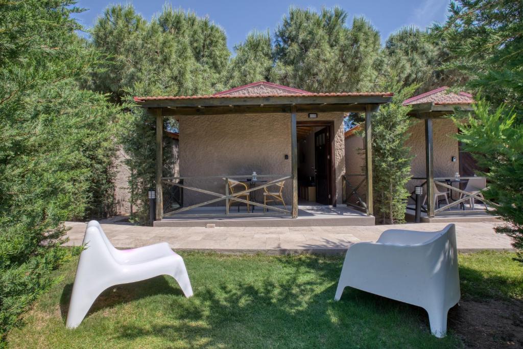 two white chairs in the grass in front of a house at AEGEAN Apartments - Bungalows in Alacati