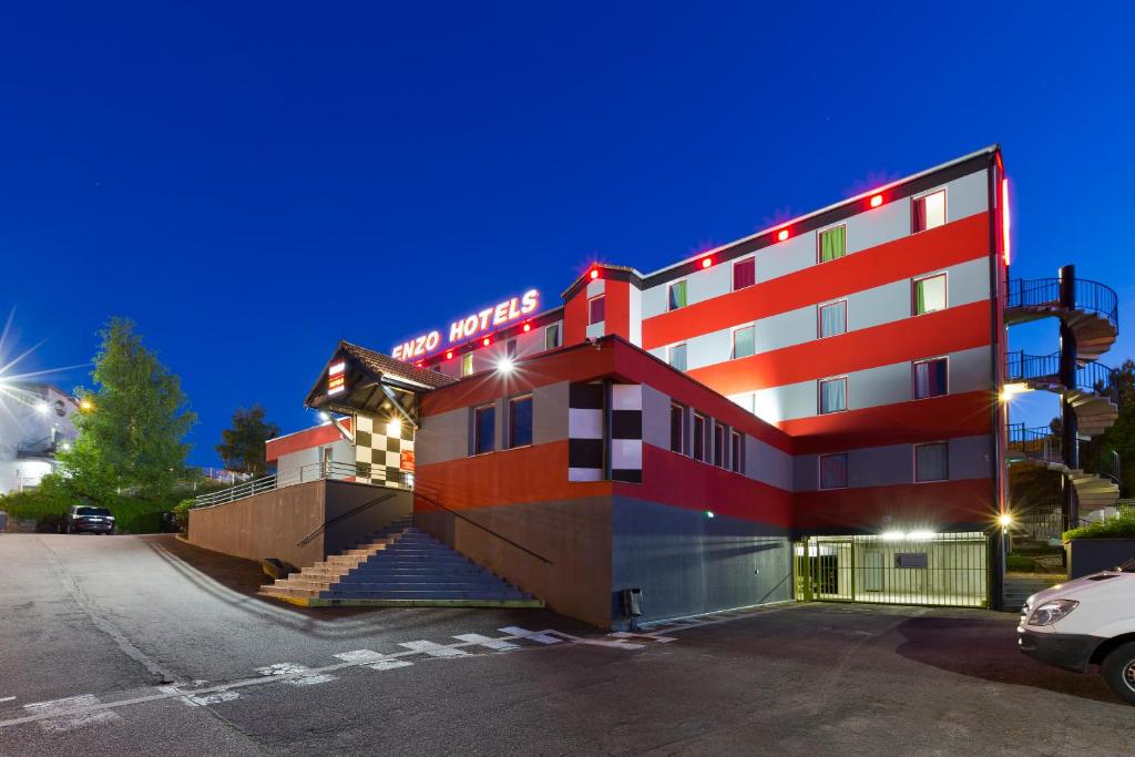 ein großes rotes Gebäude mit Treppen auf einem Parkplatz in der Unterkunft Enzo Hotels Nancy Frouard by Kyriad Direct in Frouard