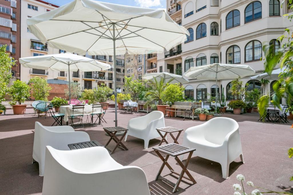 a patio with white chairs and tables and umbrellas at Mihlton Barcelona Boutique B&B in Barcelona