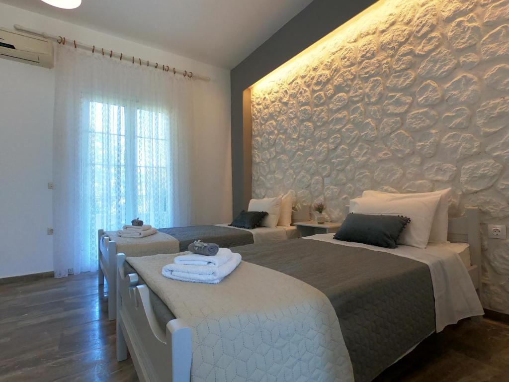 a bedroom with two beds and a stone wall at Spiridoula 1 Studios & Apartments in Sidari