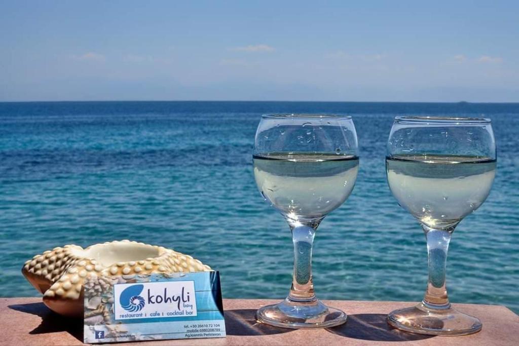 dwa kieliszki białego wina siedzące na stole blisko oceanu w obiekcie IONIAN MARE w mieście Agios Ioannis Peristerion