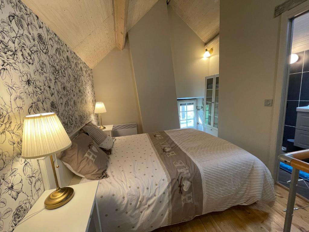 een slaapkamer met een bed en een tafel met een lamp bij Le logis des Remparts, au coeur de Sancerre in Sancerre