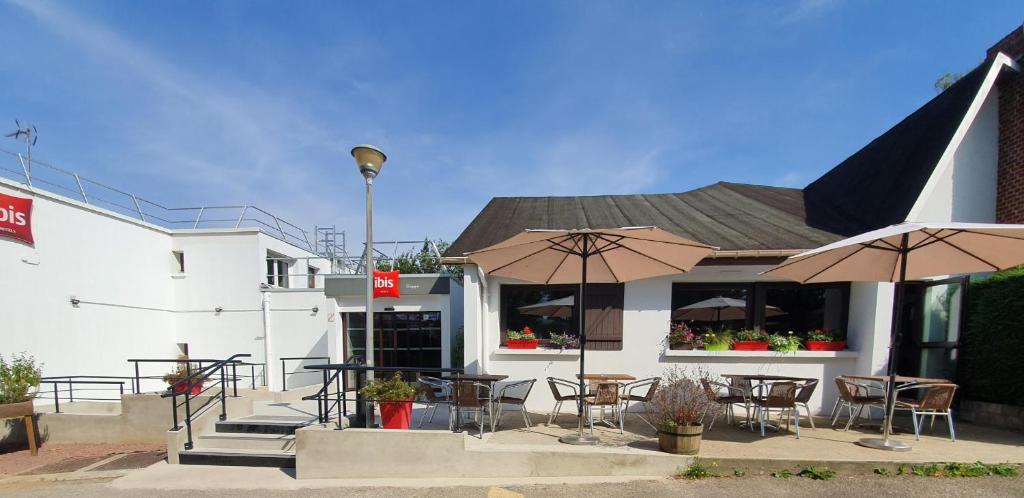 un restaurant avec des tables, des chaises et des parasols dans l'établissement ibis Dieppe Le Val Druel, à Dieppe