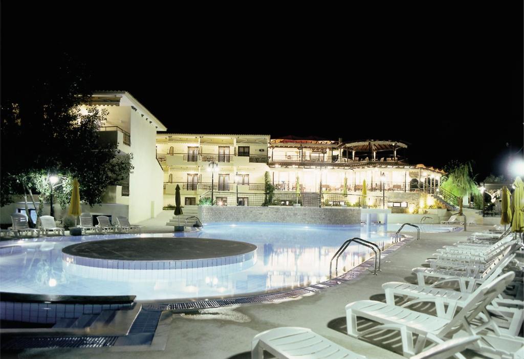 a swimming pool at night with chairs and a building at Hotel Makednos in Nikiti