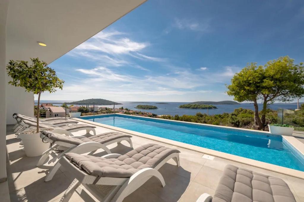 a pool with chairs and a view of the water at Villa Marvela - Family 4 Bedroom in Maslinica