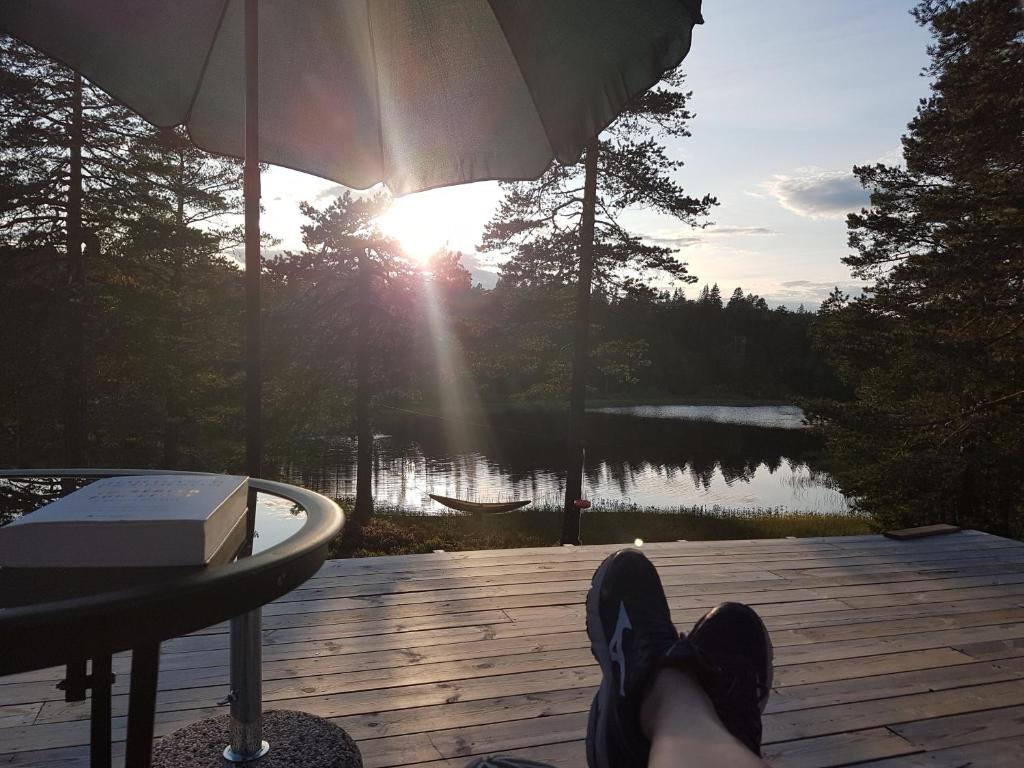 una persona con los pies en una terraza con vistas a un lago en Solhytta Fantastisk beliggenhet! Hytte til leie på Skrim!, en Kongsberg